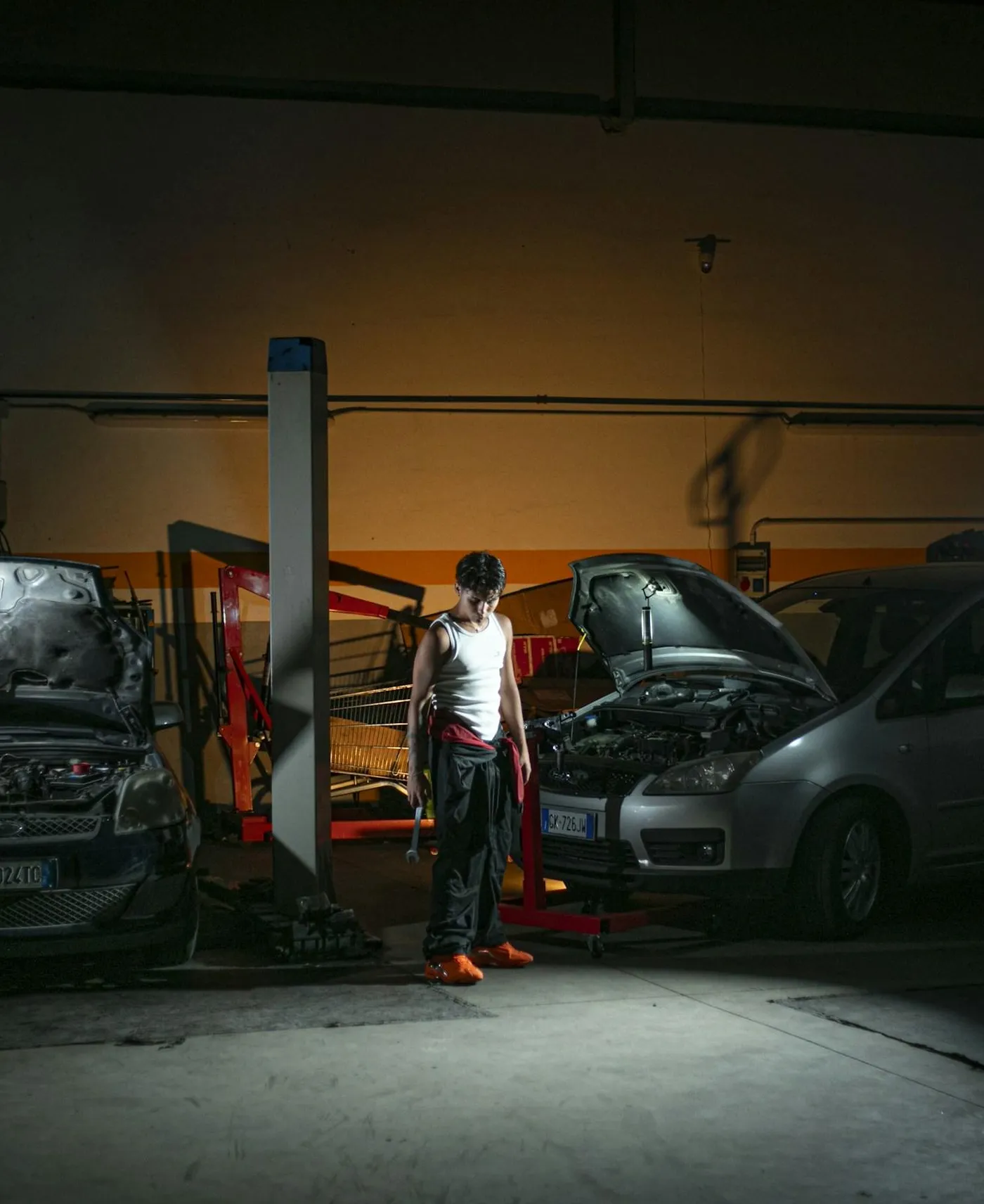 Técnico en el taller junto a vehículos con el capó abierto