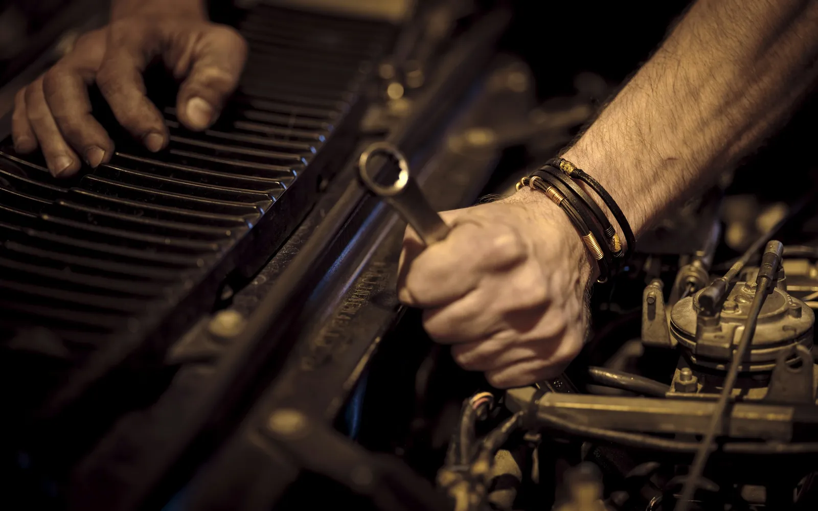 Manos ajustando una pieza del motor con una llave